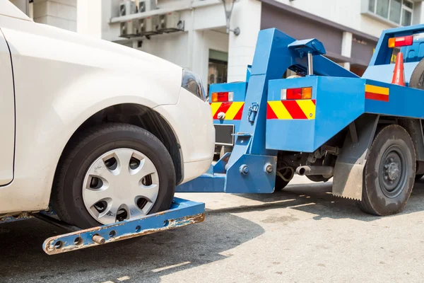 Abschleppwagen beim Abschleppen eines kaputten Autos mit Schwerpunkt auf abgeschlepptem Auto. — Stockfoto