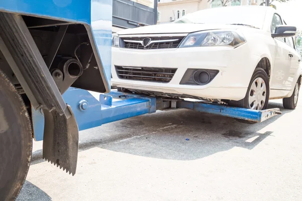 Abschleppwagen beim Abschleppen eines kaputten Autos mit Schwerpunkt auf abgeschlepptem Auto. — Stockfoto