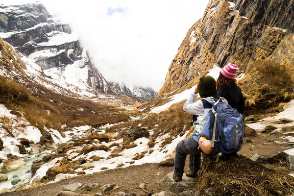 Dos excursionistas descansando mientras disfrutan de la serena vista de la caminata nevada en ruta al campamento base de Annapurna, Nepal — Foto de Stock