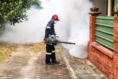 Worker fogging residential area with insecticides to kill aedes clipart