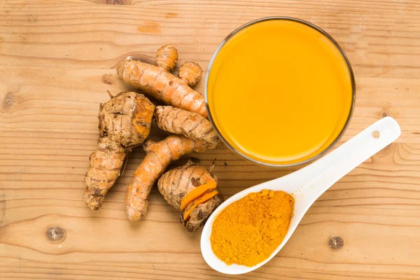 Rădăcini sănătoase de turmeric băuturi într-un pahar transparent pe lemn s — Fotografie, imagine de stoc