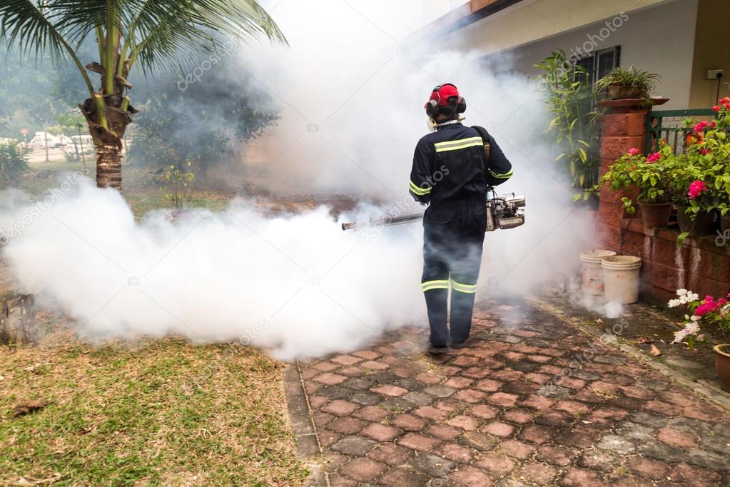 Worker fogging residential area with insecticides to kill aedes mosquitoes