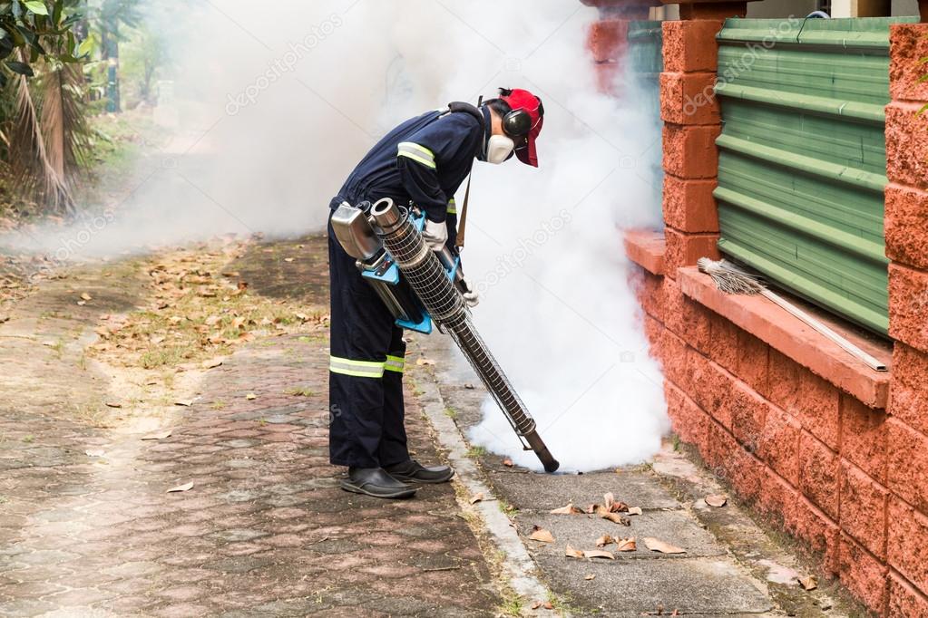 Worker fogging drain at residential area with insecticides to kill