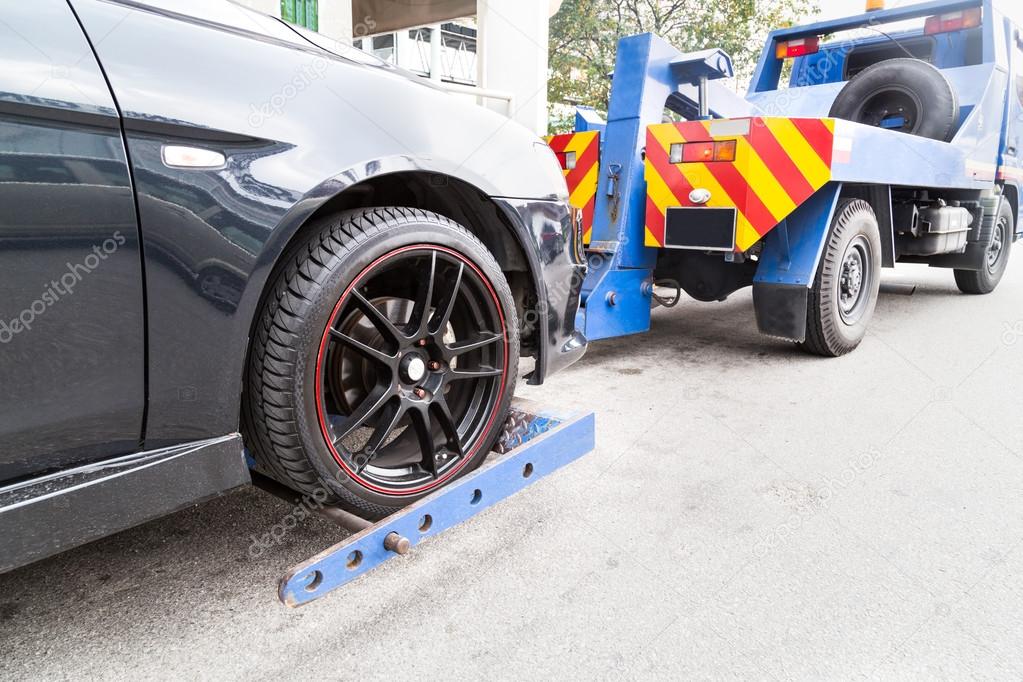 Tow truck towing a broken down car on the street