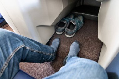 Uçuş sırasında geniş bacakları olan birinci sınıf yolcu rahat seyahat deneyimi için ayakkabılarını çıkardı.