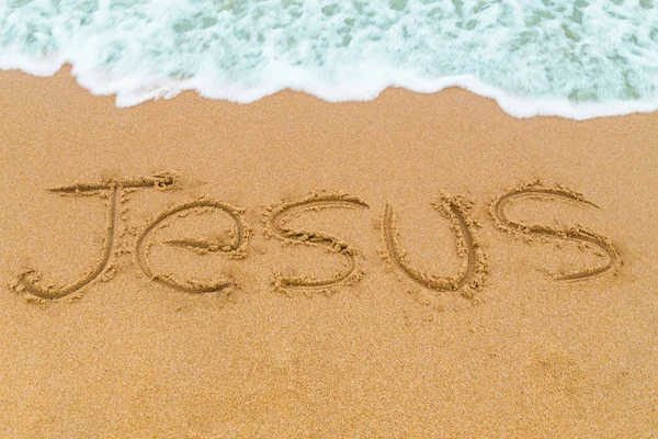 JESUS inscription written on sandy beach with wave approaching — Stock Photo, Image