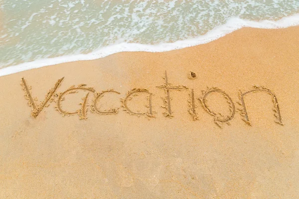 Urlaubs-Inschrift auf Sandstrand mit Wellenanflug geschrieben — Stockfoto