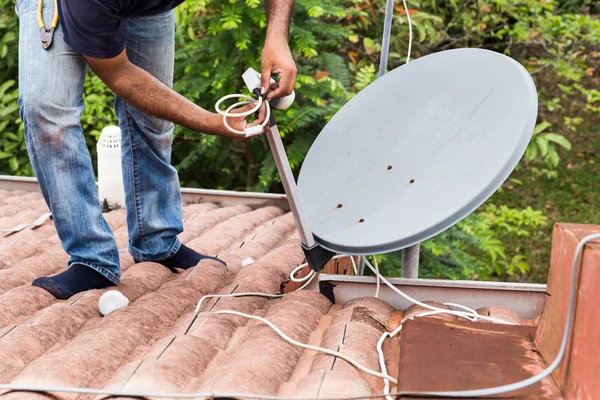 Arbeiter installiert Satellitenschüssel und Antenne auf dem Dach — Stockfoto