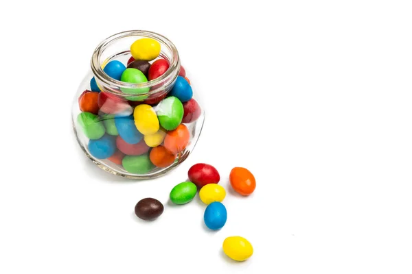 Transparent glass jar with colorful chocolate candies on white b — Stock Photo, Image