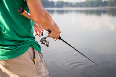 Man enjoying recreational fishing at a lake on a beautiful morning