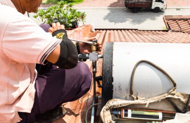 Closeup işçi maintena sırasında çatıda güneş enerjili su ısıtıcı sabitleme