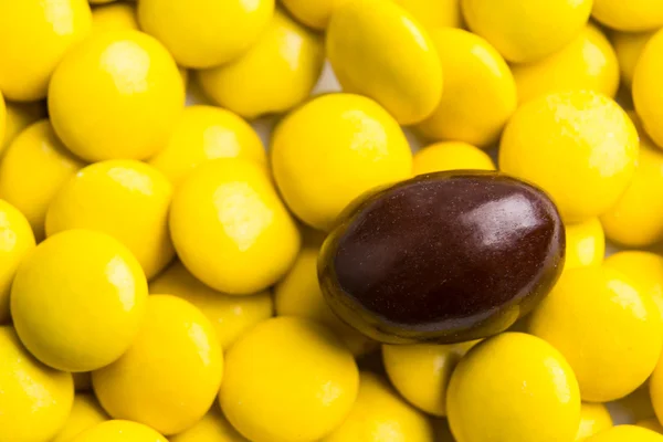 Concéntrate en dulces de chocolate marrón contra montones de caramelos amarillos — Foto de Stock