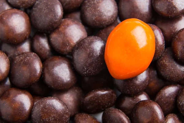 Fokusera på orange choklad godis mot högar av brunt godis — Stockfoto