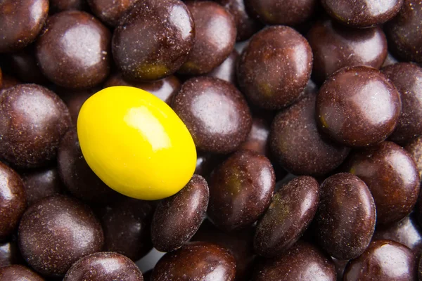 Focus op gele chocoladesuikergoed tegen hoopjes van bruin snoepjes — Stockfoto