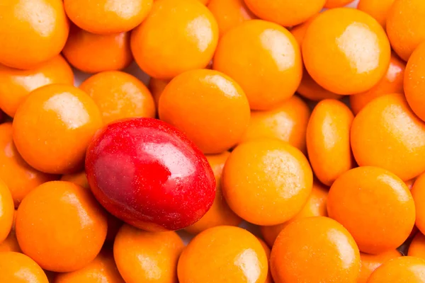 Concentrați-vă pe bomboane de ciocolată roșie împotriva grămezilor de bomboane portocalii — Fotografie, imagine de stoc