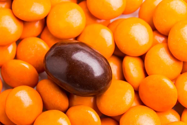 Concéntrate en dulces de chocolate marrón contra montones de caramelos naranjas — Foto de Stock