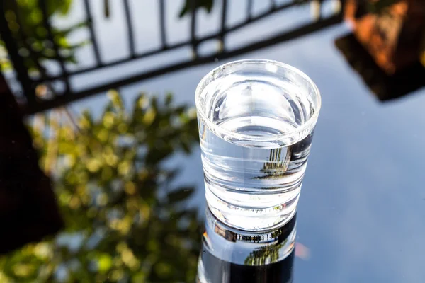 Agua refrescante en vidrio transparente con reflexión contra el cielo azul y los veranos —  Fotos de Stock