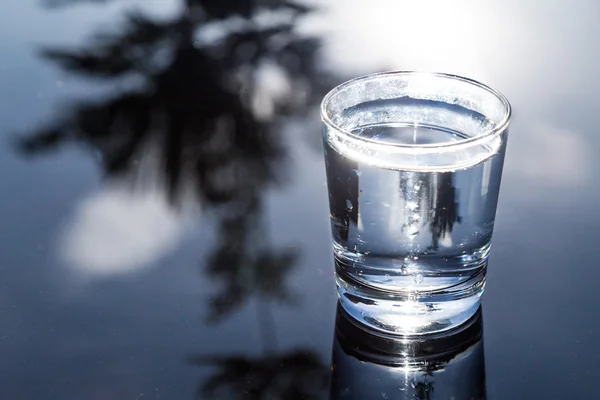 Verfrissende water in transparant glas met reflectie tegen blauwe hemel — Stockfoto