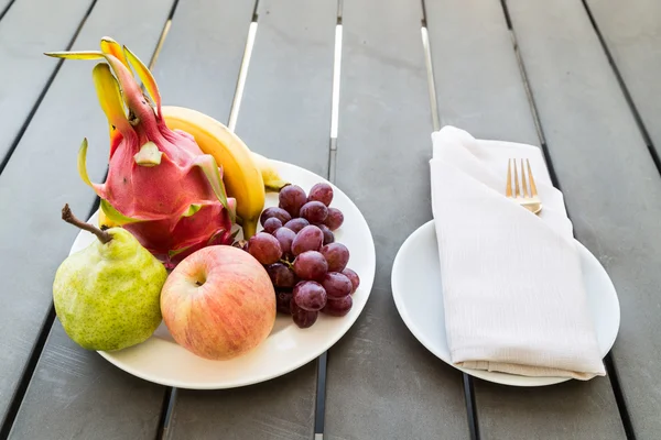 Frutas mistas no prato servido na mesa com garfo de guardanapo — Fotografia de Stock