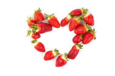 Heaps of strawberries form heart shape on white background