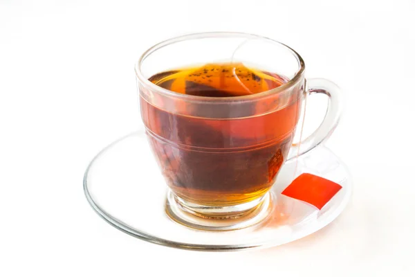 Горячий чай с пакетиком чая в прозрачной чашке и блюдце — стоковое фото