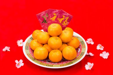 Mandarin oranges and red packets with Chinese Good Luck character