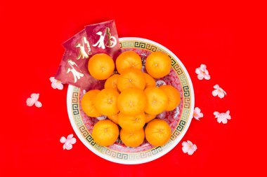Mandarin oranges and red packets with Chinese Good Luck character