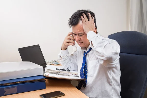 Stressful and frustrated Asian manager talking on telephone in office — Stock Photo, Image