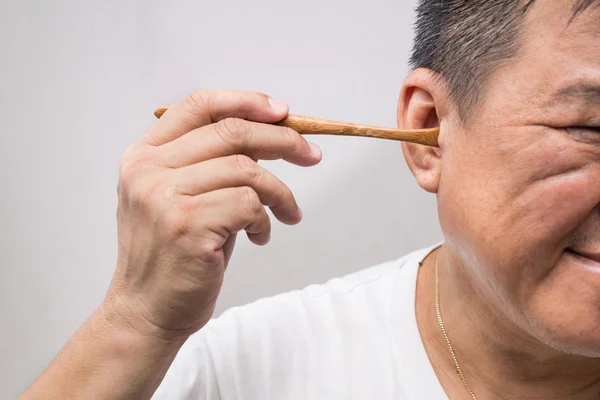 Человек негигиенично чистит ухо деревянной палкой — стоковое фото