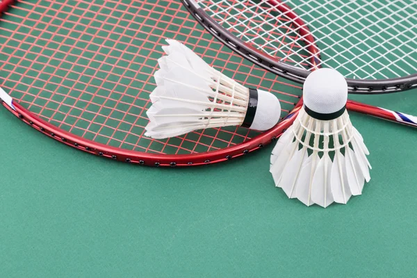 Dois novos badminton shuttlecock com raquetes no campo de esteira verde — Fotografia de Stock