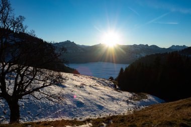 Gün batımından kısa bir süre önce Alp çayırları ve sisli bir vadi karla kaplandı.