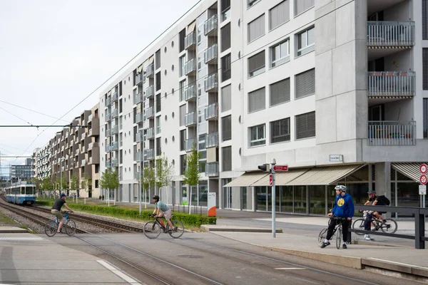Opfikon, Suiza - 19 de abril de 2020: Ciclistas cruzando el tranvía frente a las modernas fachadas de Glattpark — Foto de Stock