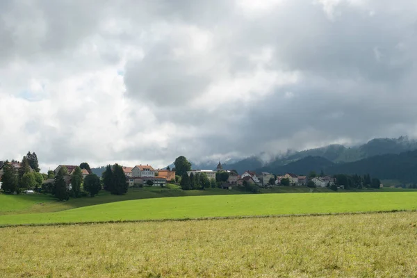 LAuberson, un pequeño pueblo en las montañas del Jura suizo, rodeado de prados — Foto de Stock