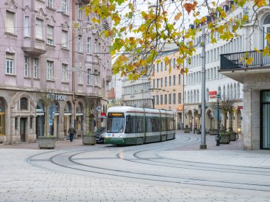 Bahnhofstrasse, Almanya 'nın Augsburg eyaletinde yer alan tarihi bir caddedir. Sonbahar renklerinde ağaçlar, eski binalar ve arka planda bir tramvay.. 