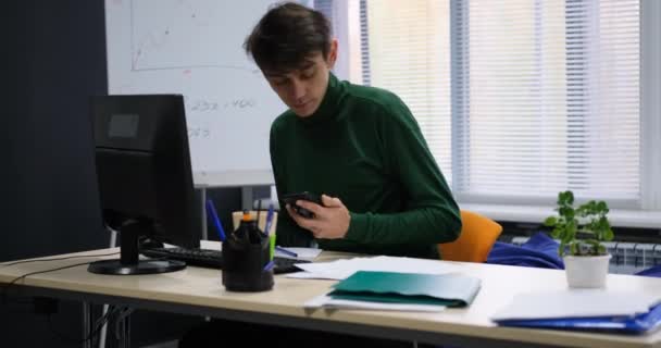 Empresario sentado en la oficina y usando el teléfono inteligente. — Vídeo de stock