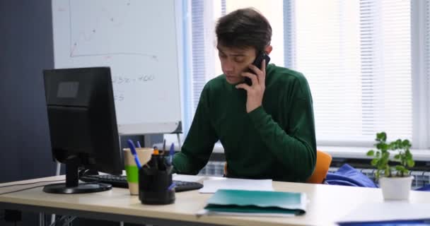 Бизнесмен выступает по телефону и проверяет бухгалтерские отчеты — стоковое видео