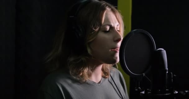 아름다운 가수가 전문 녹음실에서 마이크로 노래를 부르고 있다. — 비디오