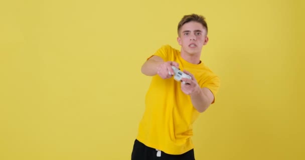 Joven hombre jugando videojuego y celebrando la victoria sobre el fondo amarillo — Vídeos de Stock