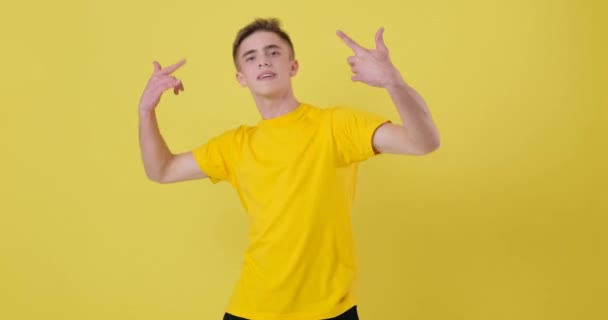 Безтурботний молодий чоловік танцює на жовтому тлі — стокове відео