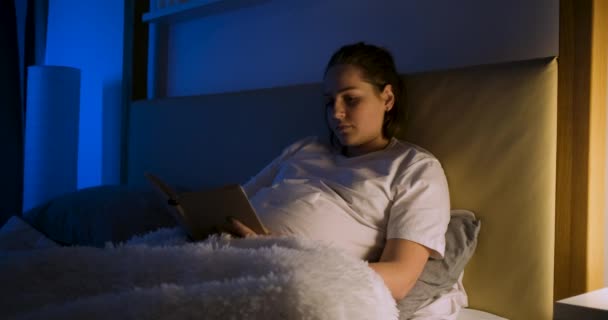 Hamile kadın kitap okuyor ve karnına dokunuyor.. — Stok video