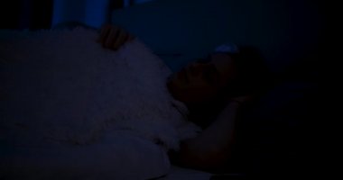 Yatakta yatan bir kadın uyanır ve ışığı açar..