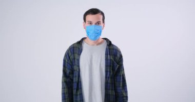 Kamerada poz veren koruyucu maskeli bir adam.