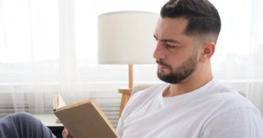 İş adamı kanepede oturmuş karantinada kitap okuyor.