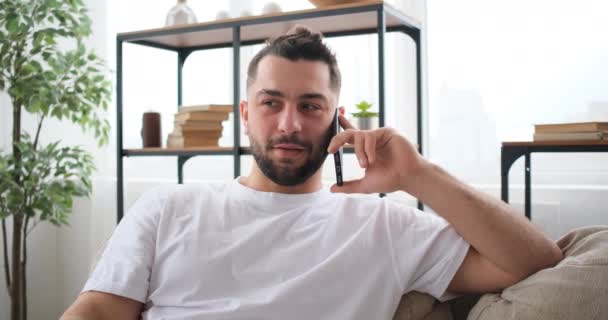 Homem de meia idade falando no smartphone em casa no sofá — Vídeo de Stock