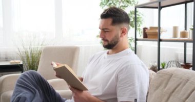 Adam kanepede kitap okuyor. 