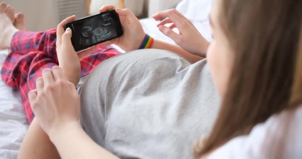 Pareja lesbiana mirando la imagen de ultrasonido en el teléfono inteligente — Vídeos de Stock