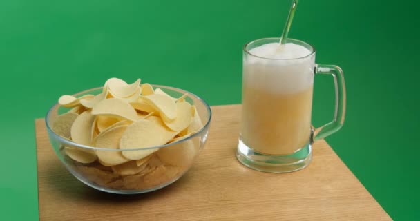 Aardappelchips en bier worden in een glas gegoten — Stockvideo