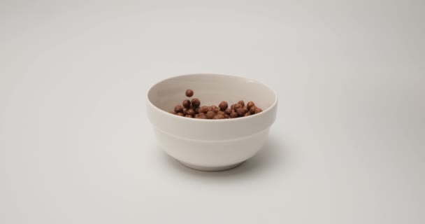 Slow motion chocolate crunchy balls for breakfast falling into white bowl — 비디오