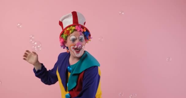 Смешной клоун пытается лопнуть мыльные пузыри — стоковое видео