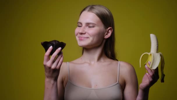 Крупный план женщины, делающей выбор между бананом и тортом — стоковое видео